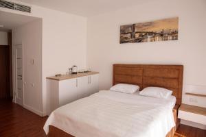 a bedroom with a white bed with a wooden headboard at SkyTech Most City Hotel 19 floor PANORAMIC VIEW in Dnipro