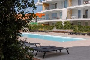 - une piscine avec bancs à côté d'un bâtiment dans l'établissement Very pleasant apartment with communal pool, à Nieuport