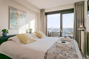 een slaapkamer met een groot wit bed en een raam bij Sunny and comfortable 2 bedroom appartement with stunning Sea-view and 2 terraces in Knokke-Heist