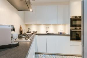 une cuisine avec des armoires blanches et une cuisinière dans l'établissement Huswell - Authentic townhouse near the beach - pets welcome!, à Blankenberge