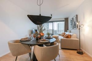 a living room with a table and chairs and a couch at Modern apartment close to the beach with common pool in Ostend