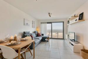 een woonkamer met een blauwe bank en een tafel bij Cosy apartment with amazing beach view in Oostende