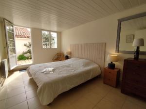 a bedroom with a large bed and two windows at Maison Pimpino face à la plage in Saint-Georges-dʼOléron