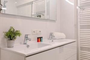 a white bathroom with a sink and a mirror at Huswell - Comfortable 2 bedroom apartment with sea-view in Knokke-Heist +12 photos