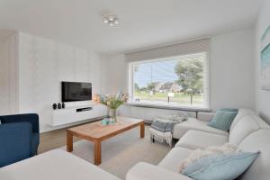 een woonkamer met een bank en een tafel bij Bright and spacious bungalow with garden near the beach in Middelkerke