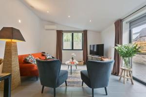 uma sala de estar com um sofá laranja e cadeiras em Charming house in the beautiful village Donk with a terrace em Maldegem