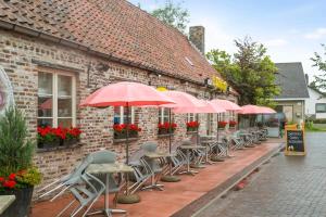 una fila de mesas y sillas con sombrillas fuera de un edificio en Charming house in the beautiful village Donk with a terrace en Maldegem