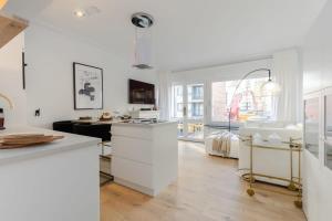 een keuken met witte kasten en een groot raam bij Stylish apartment with cosy fireplace near the sea in Knokke-Heist