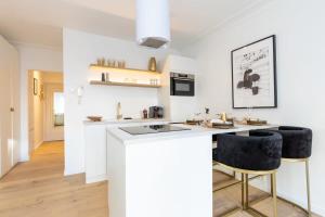een witte keuken met een aanrecht en krukken bij Stylish apartment with cosy fireplace near the sea in Knokke-Heist