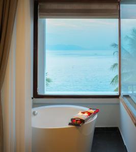 une baignoire dans une salle de bain avec une grande fenêtre dans l'établissement Alibu Resort Nha Trang, à Nha Trang