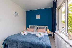 Charming beachside villa with private terrace في كنوك هايست: غرفة نوم زرقاء عليها سرير بثلاث مناشف