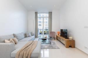 a white living room with a couch and a tv at Fabulous duplex apartment in a recently renovated town house in Ostend