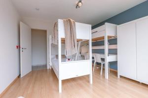 Un dormitorio con dos literas y una mesa. en Huswell - Charming apartment near the beach with balcony, en De Panne
