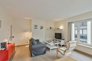 een woonkamer met een bank en een tv bij Lovely Family Apartment 50 meters from the Sea in De Haan