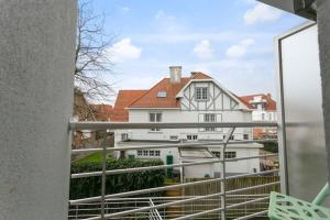 een balkon met uitzicht op een wit huis bij Lovely Family Apartment 50 meters from the Sea in De Haan