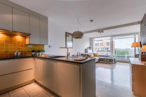 Una cocina con gabinetes blancos y una ventana grande. en Huswell - Charming apartment near the beach with balcony, en De Panne