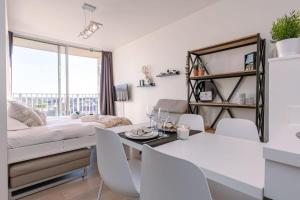 Una sala de estar con una cama, una mesa y sillas. en Huswell - Modern studio near the sea and beach, en Nieuwpoort