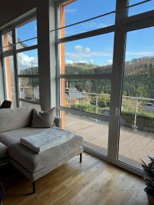 uma sala de estar com um sofá e uma grande janela em Stilvolle Ferienwohnung in ruhiger Lage em Willingen