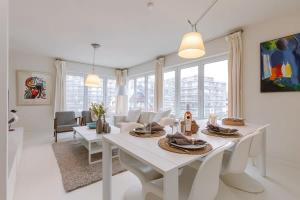 a white living room with a white table and chairs at Pleasant Apartment for Families close to the beach in De Haan