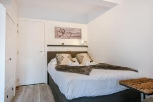 a bedroom with a large bed with white sheets at Charming studio with terrace nearby the beach in Middelkerke