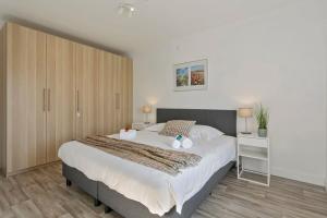 um quarto com uma grande cama branca e pisos em madeira em Charming apartment near the beach of Zeebrugge em Bruges