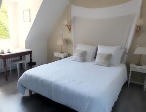 een slaapkamer met een wit bed en een bureau bij Ailes et Iles in Pleudaniel