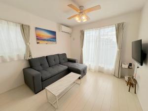 - un salon avec un canapé et un ventilateur de plafond dans l'établissement グランディオーソ沖縄ヴィラ恩納3, à Onna