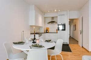 uma sala de jantar branca com uma mesa e cadeiras brancas em Stylish apartment with terrace and balcony em Antuérpia