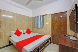 um quarto com uma cama com almofadas vermelhas e uma secretária em Super OYO RKH Residency em Chennai