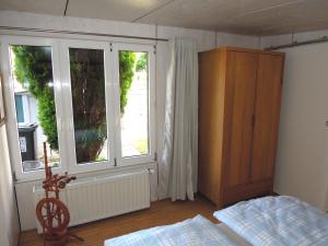 Nollingen的住宿－Stilvolle Ferienwohnung in Rheinfelden，一间卧室配有一张床、一个橱柜和两个窗户
