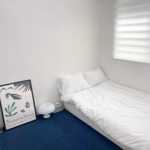 Un dormitorio con una cama blanca y una foto en el suelo en [NEW] 구디역 도보 10분/깔끔한 감성 투룸/넷플릭스 en Seúl