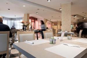 里乔内Augustus Hotel Riccione的餐厅设有桌椅,背景人员