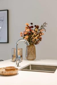 Huswell - Apartment with terrace close to the sea في أوستند: طاولة مطبخ مع حوض و مزهرية من الزهور