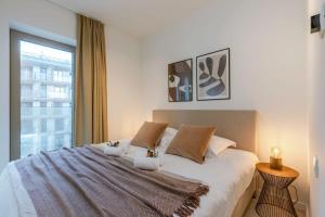 Huswell - Apartment with terrace close to the sea في أوستند: غرفة نوم بسرير كبير مع نافذة