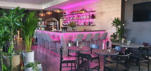 a restaurant with pink lighting and tables and chairs at Hotell Iföhus in Bromölla
