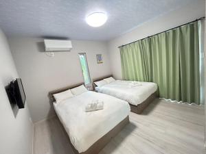 a hotel room with two beds and a window at Orange House in Hirara
