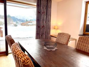 a dining room table with chairs and a large window at Alpenlodge Charivari - SommerBergBahn unlimited kostenlos in Oberstdorf