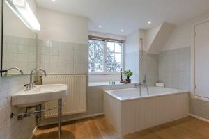 een badkamer met 2 wastafels, een bad en een raam bij Charming house Heemdael in Knokke-Le-Zoute in Knokke-Heist