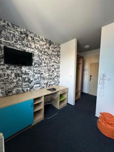 Habitación con escritorio y TV en la pared. en Sport hotel Sletiště, en Kladno