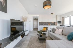ein Wohnzimmer mit einem Sofa und einem Flachbild-TV in der Unterkunft Bright apartment with seaview in Bredene