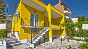a yellow building with stairs in front of it at Cosy Colorful House with Private Parking in Kavála