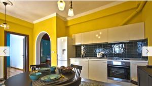 a kitchen with yellow walls and a table and chairs at Cosy Colorful House with Private Parking in Kavála