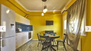 a kitchen with a table and chairs and yellow walls at Cosy Colorful House with Private Parking in Kavála +9 photos