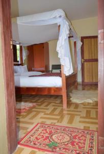 Sekenaniにあるsunshine maasai Mara safari camp in Kenyaのベッドルーム1室(天蓋付きベッド1台、ラグ付)