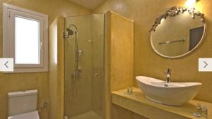 a bathroom with a sink and a shower with a mirror at Cosy Colorful House with Private Parking in Kavála