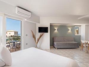 una camera con letto e un soggiorno con divano di Alexia Beach Hotel ad Agia Marina Nea Kydonias