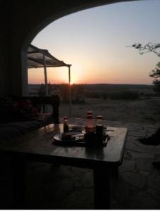 Sekenani的住宿－sunshine maasai Mara safari camp in Kenya，一张桌子,上面有饮料,背面有日落