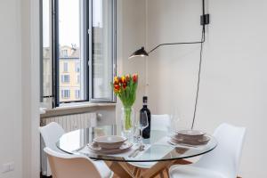 a dining room with a glass table and white chairs at Living UniQC Apartment - Duomo in Milan