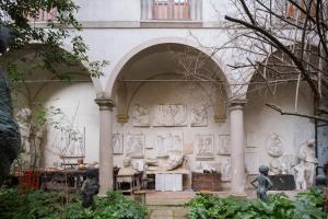 ein Gebäude mit einem Bogen mit Statuen in einem Garten in der Unterkunft L'Orto del Perseo Residenza Artistica in Florenz
