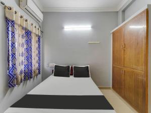 a small room with a bed and a wooden cabinet at OYO Blue jay in Chennai